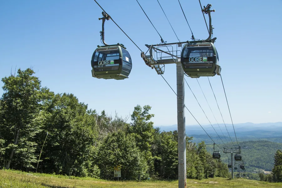 The gondola running above green forested slopes in summer