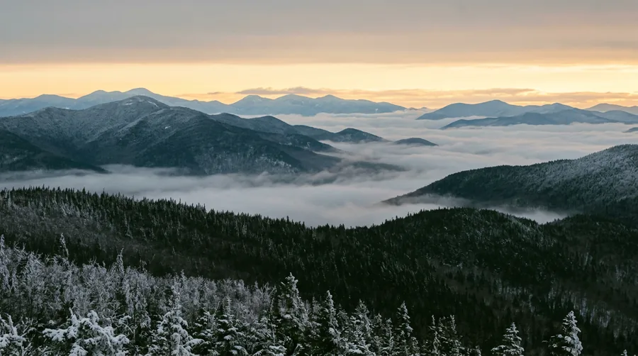 Artist's impression: layered Adirondack ridgelines at dawn with mist in the valleys